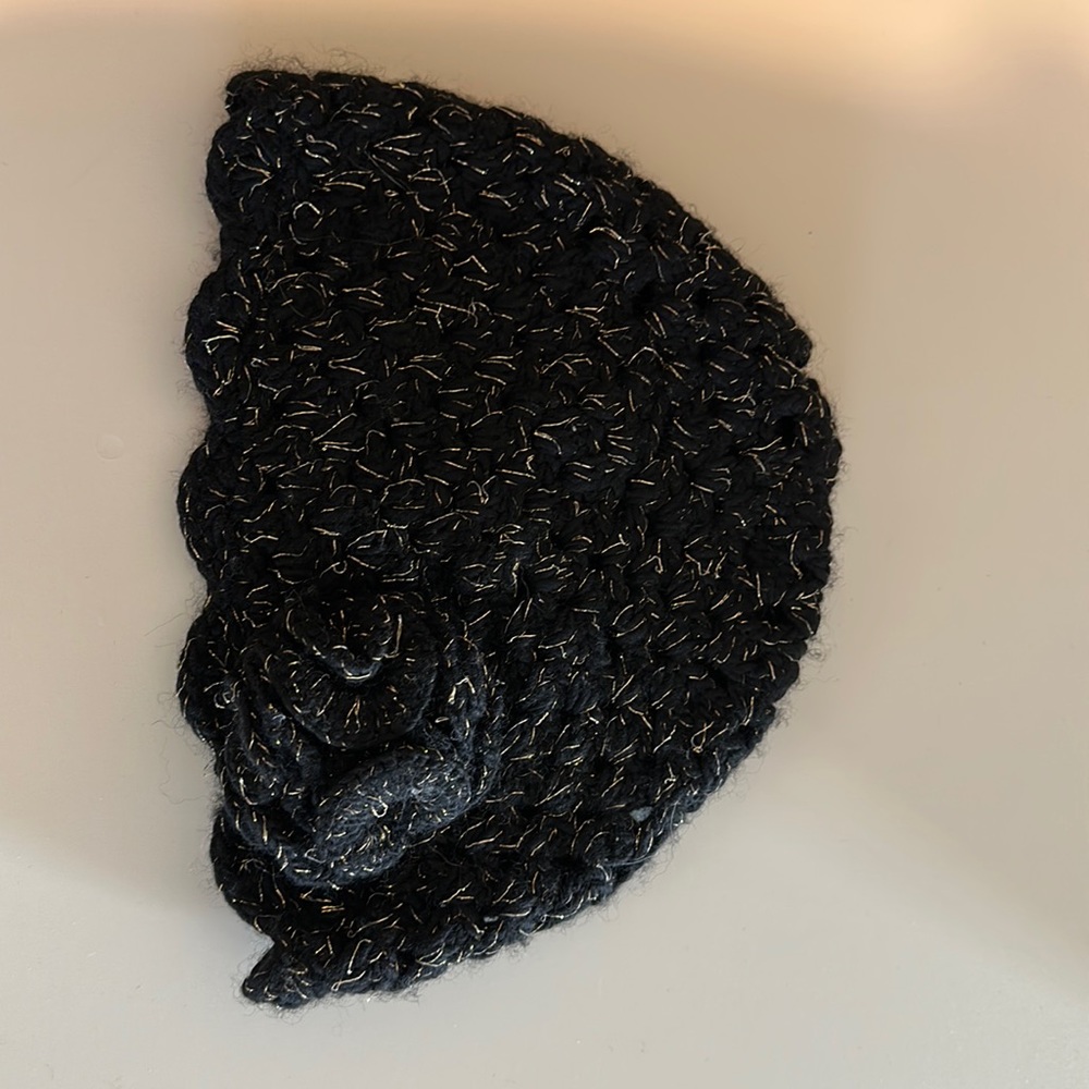 Calypso Christiane Celle black knitted hat with gold thread and floret.